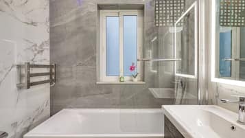 Une salle de bain moderne avec une baignoire, un grand miroir et une fenêtre donnant sur un beau paysage.