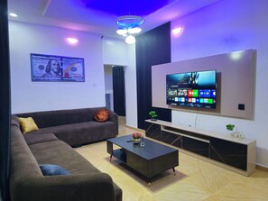 A modern living room with a sofa, coffee table, TV, and a framed currency note on the wall. - Serene 2-Bed-Apt ~ 24hrs Pwr ~ Unlimited Internet (Lagos)