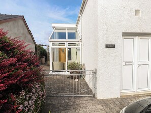 A residential property with a gated entrance, a white exterior wall, and a visible door with a nameplate. - Hafan y Tyddyn (Newport)