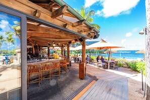 An outdoor bar area with wooden furniture and a view of the ocean. - Turtle Bay 1 Bedroom w/AC & Lanai (Kahuku)