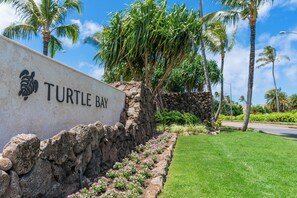 Ein Schild für Turtle Bay mit einer Steinmauer und einem gepflegten Rasen.