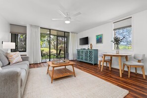 A modern living room with a sofa, coffee table, and dining area. - Turtle Bay 1 Bedroom w/AC & Lanai (Kahuku)
