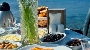 Une table dressée avec différents plats, un vase rempli de fleurs et une vue sur la mer.