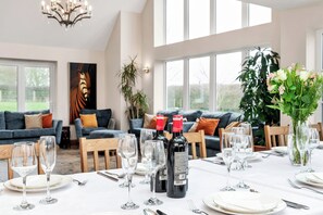 A dining area with a table set for a meal, wine bottles, and glasses. - Oldfields (Bury St Edmunds)