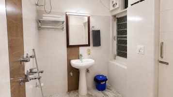 Un baño con lavamanos, espejo, toallero, ducha y ventana.