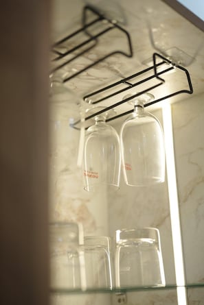 Une salle de bain dotée d’un comptoir en marbre, d’une cabine de douche en verre et d’un porte-serviettes en métal noir sur lequel sont posées plusieurs bouteilles en verre transparent.