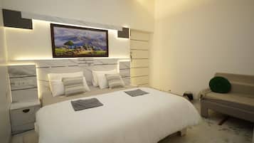 A modern bedroom with a large bed, a headboard with a painting, bedside tables, and a bench with a green pillow.