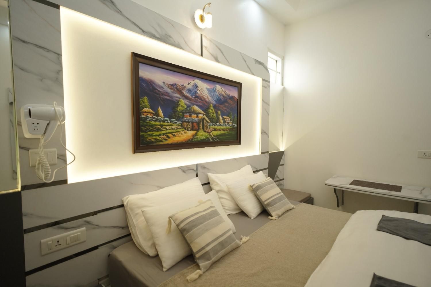 A modern bedroom with a large bed, a bedside table, a mounted picture, and a wall-mounted phone.