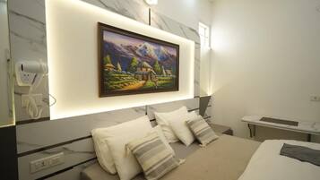 A modern bedroom with a large bed, a bedside table, a mounted picture, and a wall-mounted phone.