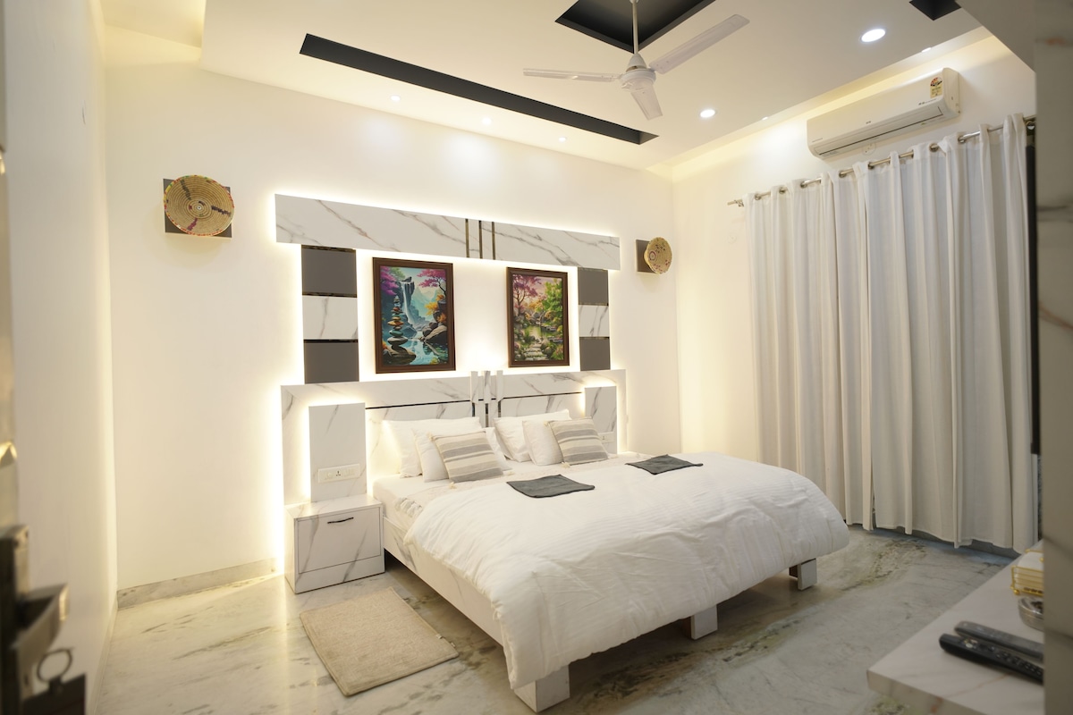 A modern bedroom with a bed, bedside tables, a ceiling fan, and artwork on the wall.