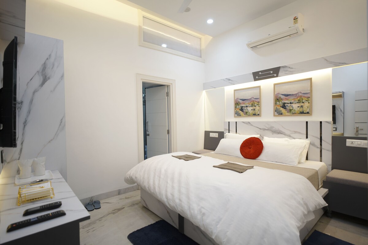 Une chambre d’hôtel moderne équipée d’un lit, de tables de chevet, d’un bureau et d’une télévision.