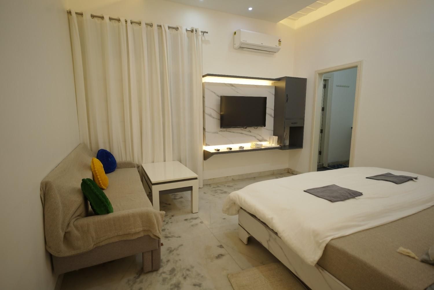 A hotel room with a bed, a desk, a chair, a television, and a window with curtains.