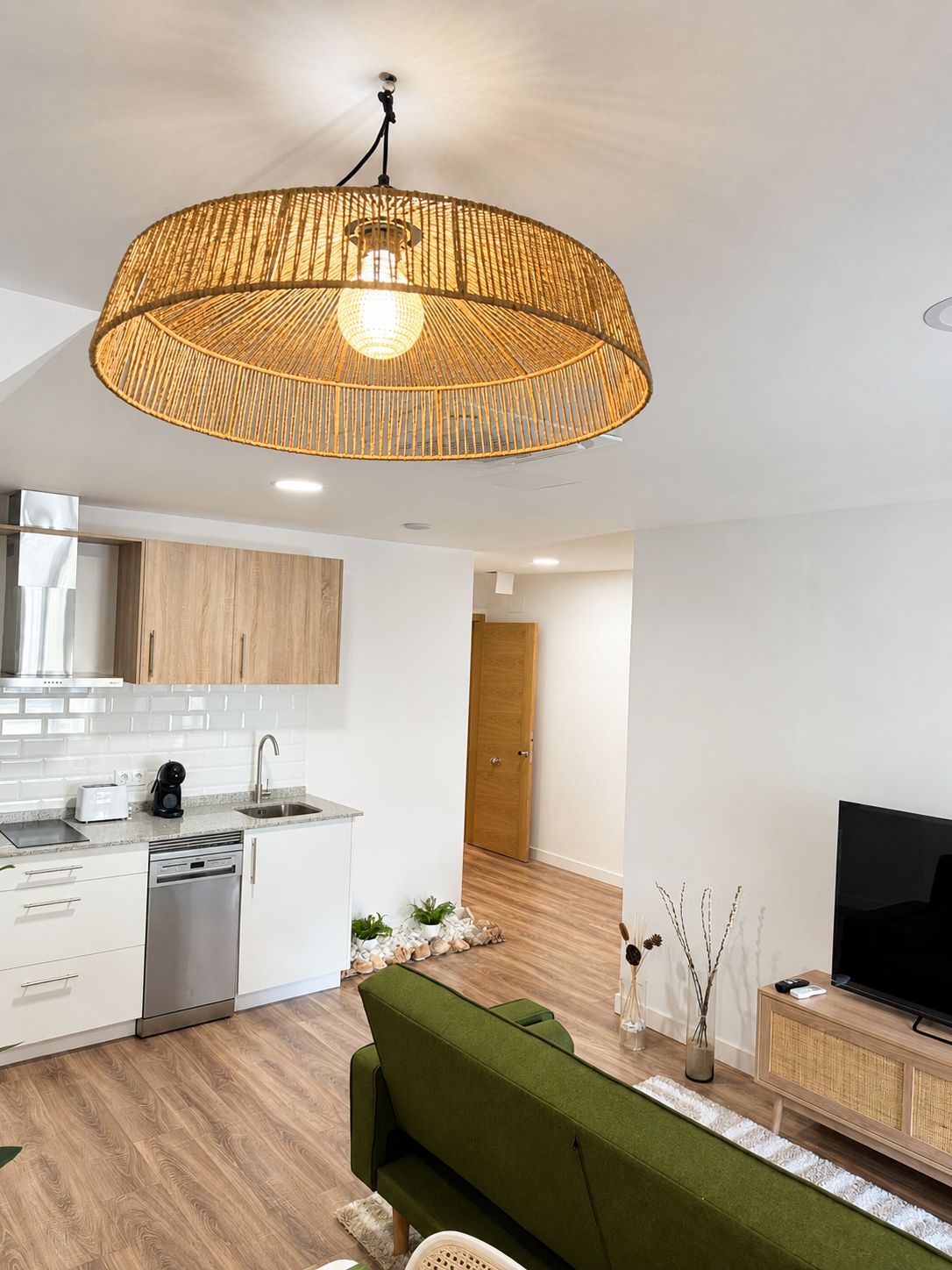A modern kitchen with white cabinets, a built-in dishwasher, and a wooden floor.