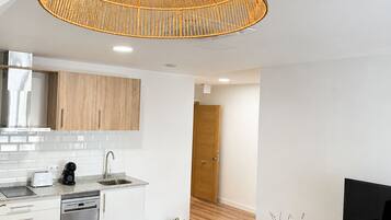 A modern kitchen with white cabinets, a built-in dishwasher, and a wooden floor.