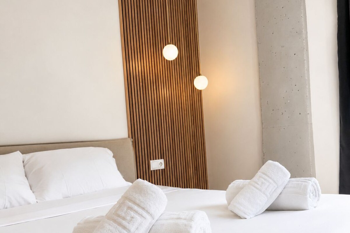 Habitación de hotel con cama, almohadas, un panel decorativo de madera y una lámpara.