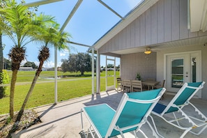 A covered outdoor area with a table and chairs, a palm tree, and a view of a grassy field. - Retreat 7 Mi to Disney! Families w/ Dogs Welcome (Kissimmee)