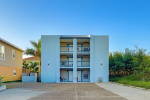 Ein mehrstöckiges Gebäude mit einer glatten Fassade und Balkonen auf jeder Etage, bewölkter Himmel.