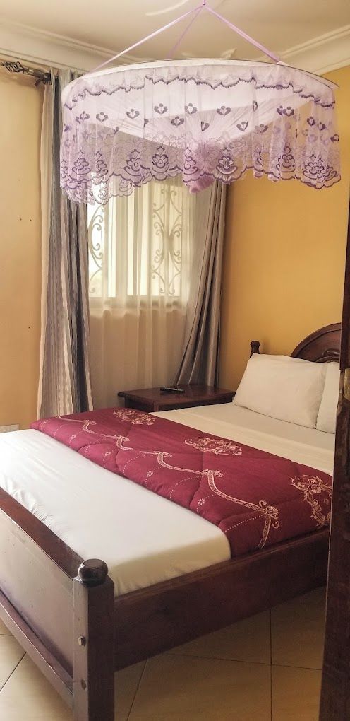 A bed with a canopy, a bedside table, and curtains.