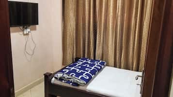 Una habitación con una cama, un televisor de pantalla plana en la pared y una cortina.