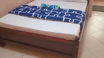 A single bed with a wooden frame, white bedding, and a blue patterned blanket.