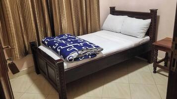 A single bed with a wooden frame, a white mattress, and a blue patterned blanket.