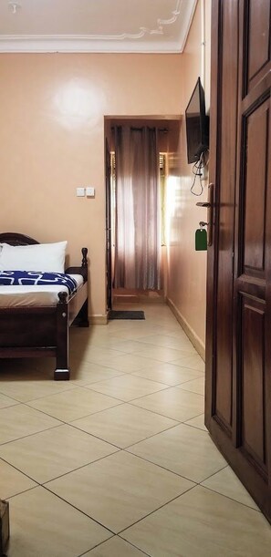 A hotel room with a bed, a television mounted on the wall, and a wooden door.