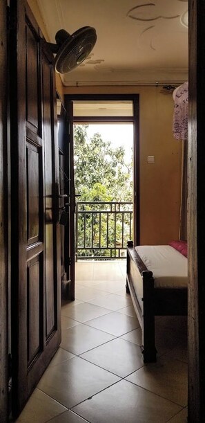 Una habitación con cama, balcón y ventilador.