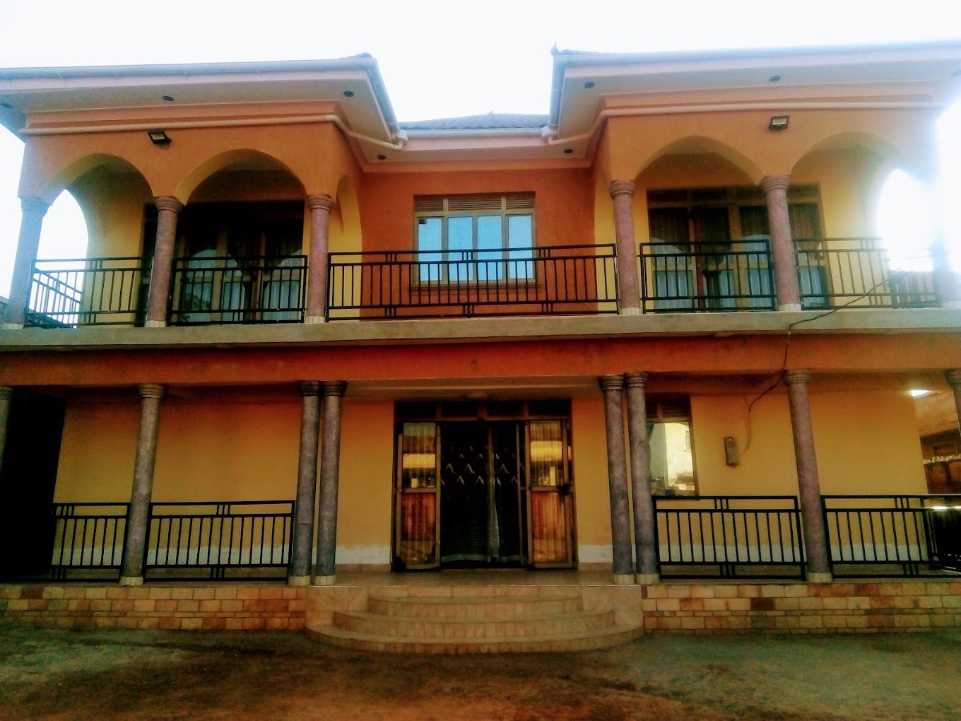 A two-story building with a balcony on the upper floor, a front entrance with a door, and a set of stairs leading to the entrance.