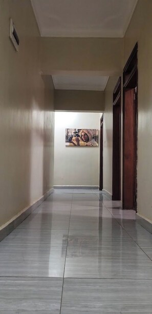 A hallway with a tiled floor, a painting on the wall, and a door at the end. - Race Hotel Mbale (Mbale)