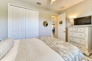 Un dormitorio con cama, cómoda, televisor y puerta que da a un baño.
