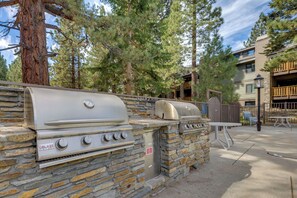 An outdoor grill area with stone walls, a barbecue grill, and a gas stove. - Steps to Slopes! Mammoth Mountain Condo (Mammoth Lakes)