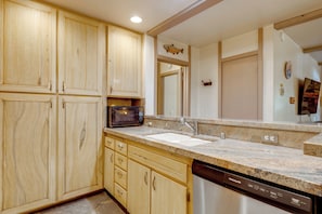 A kitchen with wooden cabinets, a microwave, a sink, and a dishwasher. - Steps to Slopes! Mammoth Mountain Condo (Mammoth Lakes)