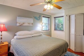 A bedroom with a bed, a nightstand, a lamp, a ceiling fan, a window with blinds, and a door. - 2 Mi to Dtwn Pensacola: Historic Home w/ Patio! (Pensacola)