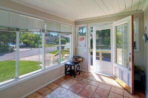 Quarto com janelas amplas, uma porta e uma pequena mesa com um objeto decorativo.
