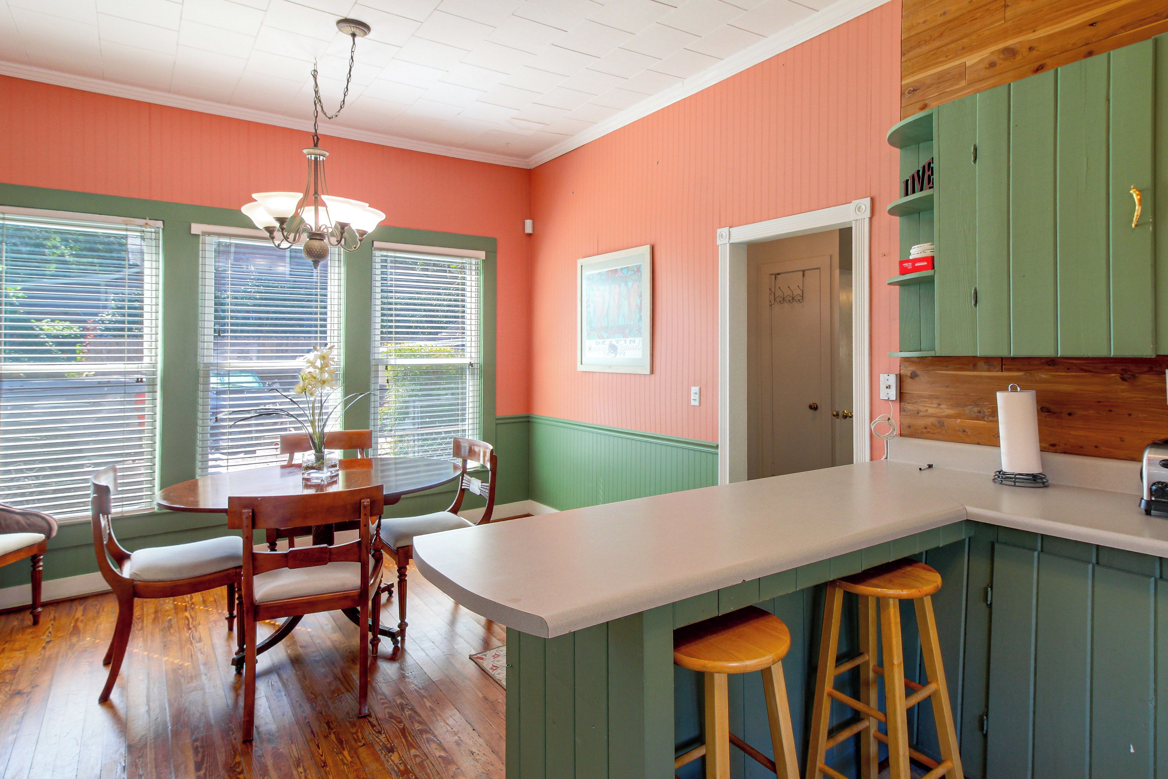 A kitchen with a dining table, chairs, a chandelier, and wooden cabinets.