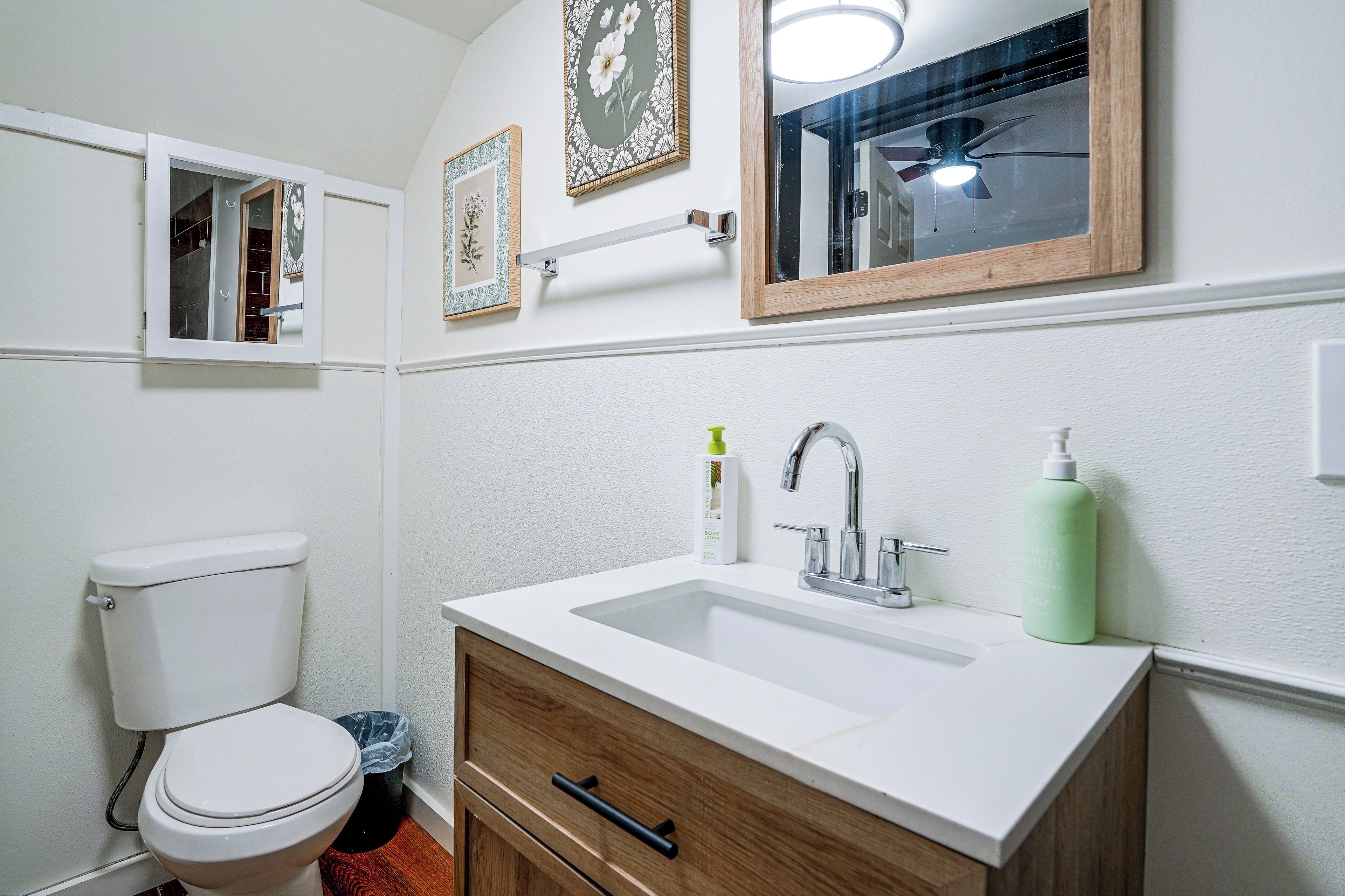 Een badkamer met toilet, wastafel en spiegel.