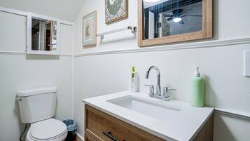 Een badkamer met toilet, wastafel en spiegel.