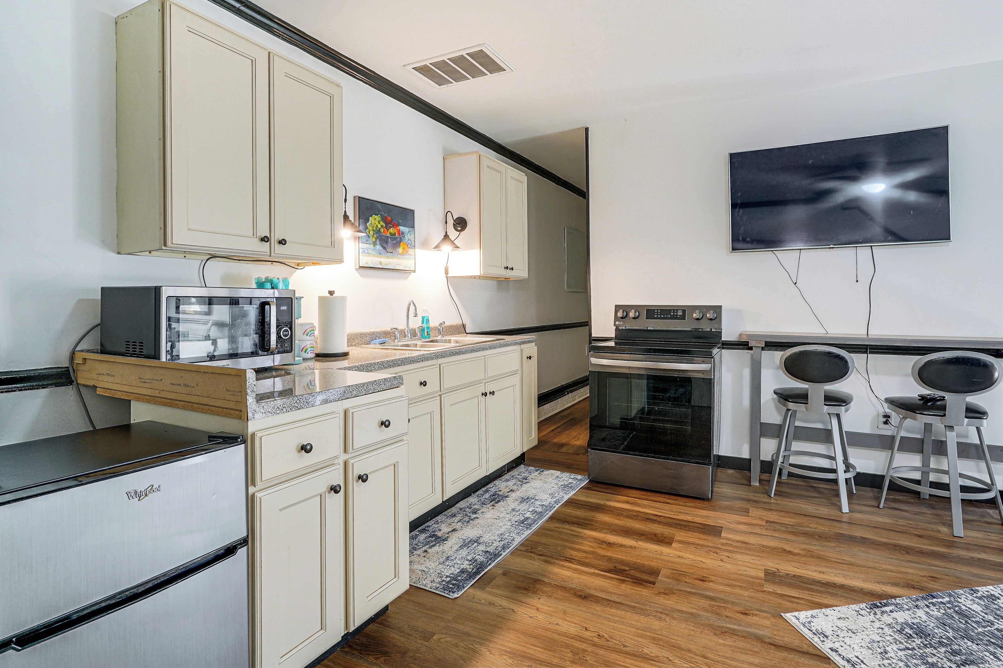 Una cocina compacta con microondas, estufa y una zona de comedor con dos sillas.