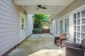 A covered porch with a ceiling fan, a brick staircase leading to a door, and wicker furniture.
