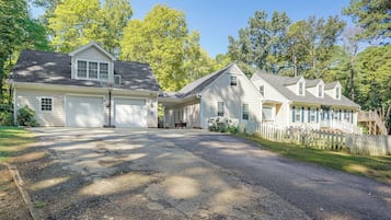A residential driveway leading to a row of houses with attached garages, surrounded by trees and a white picket fence.