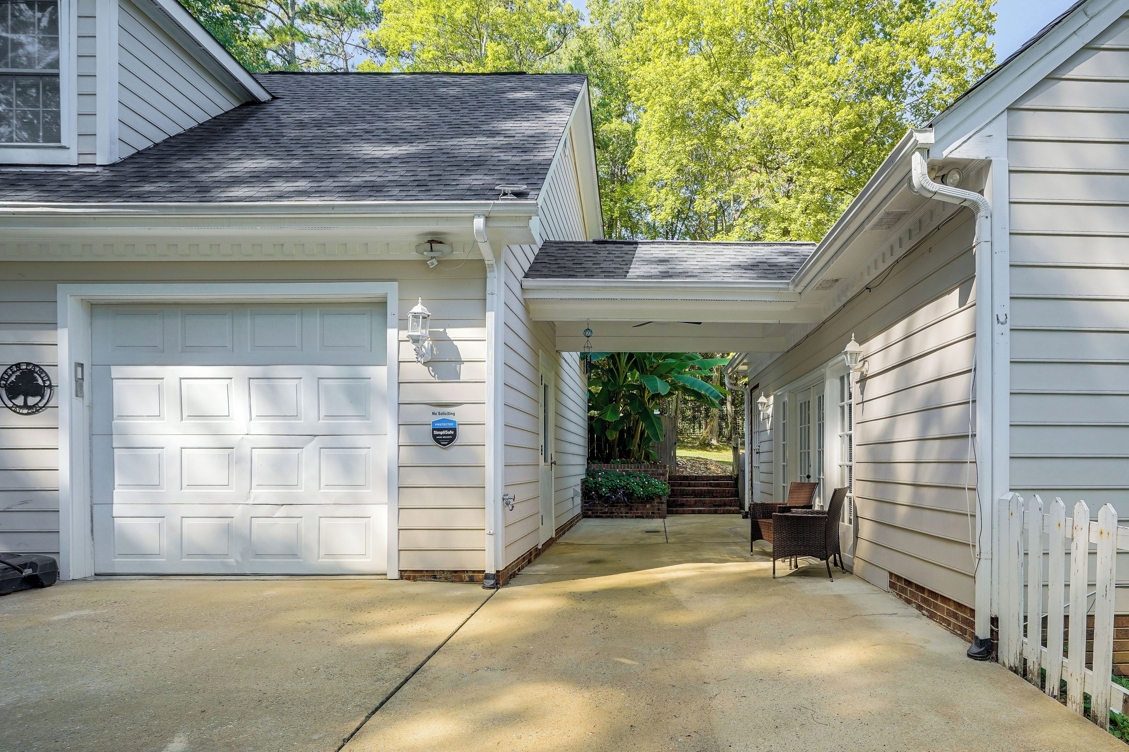 A residential property with a garage, a covered walkway, and a white picket fence.