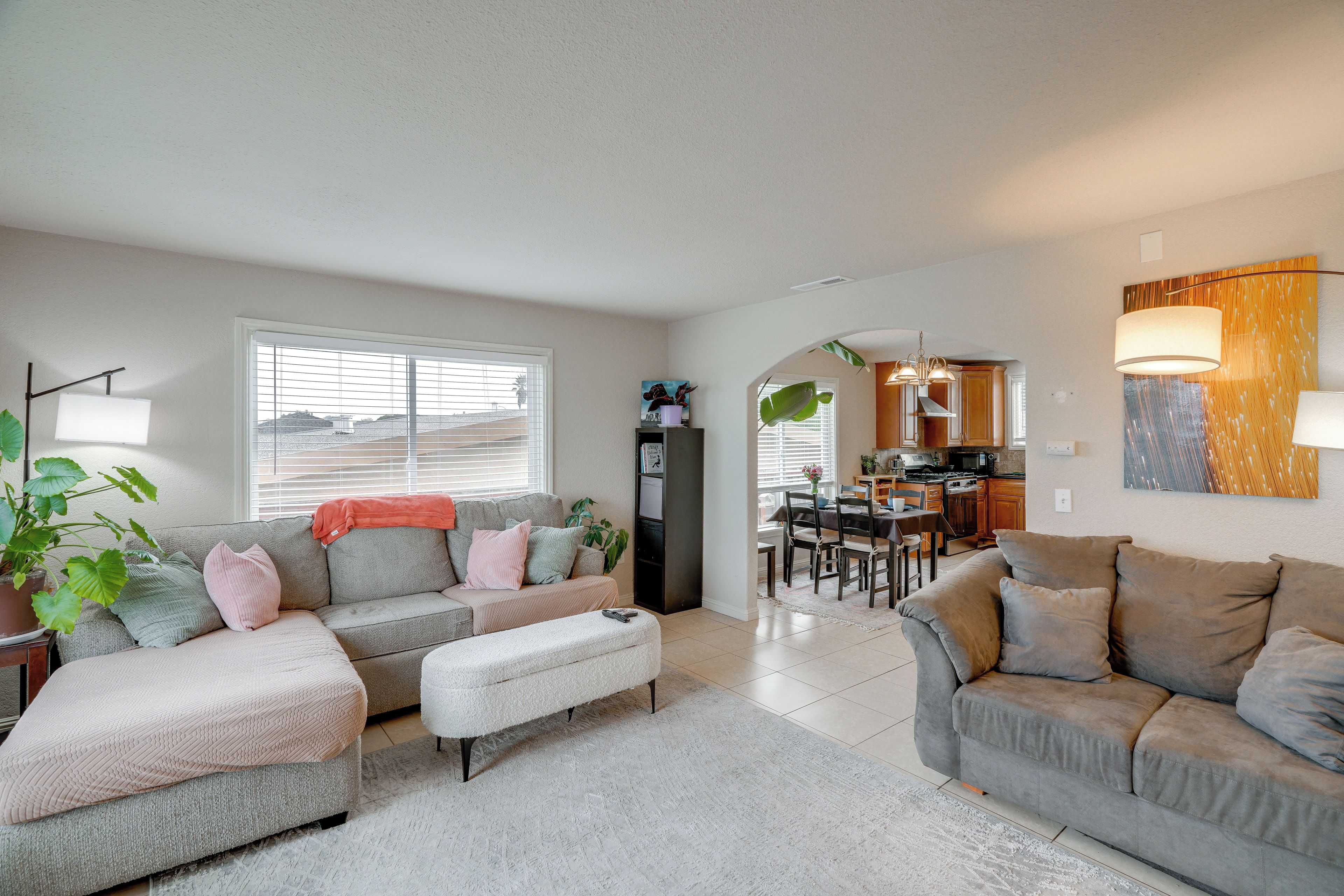A living room with a sofa, ottoman, and a dining area with a table and chairs.