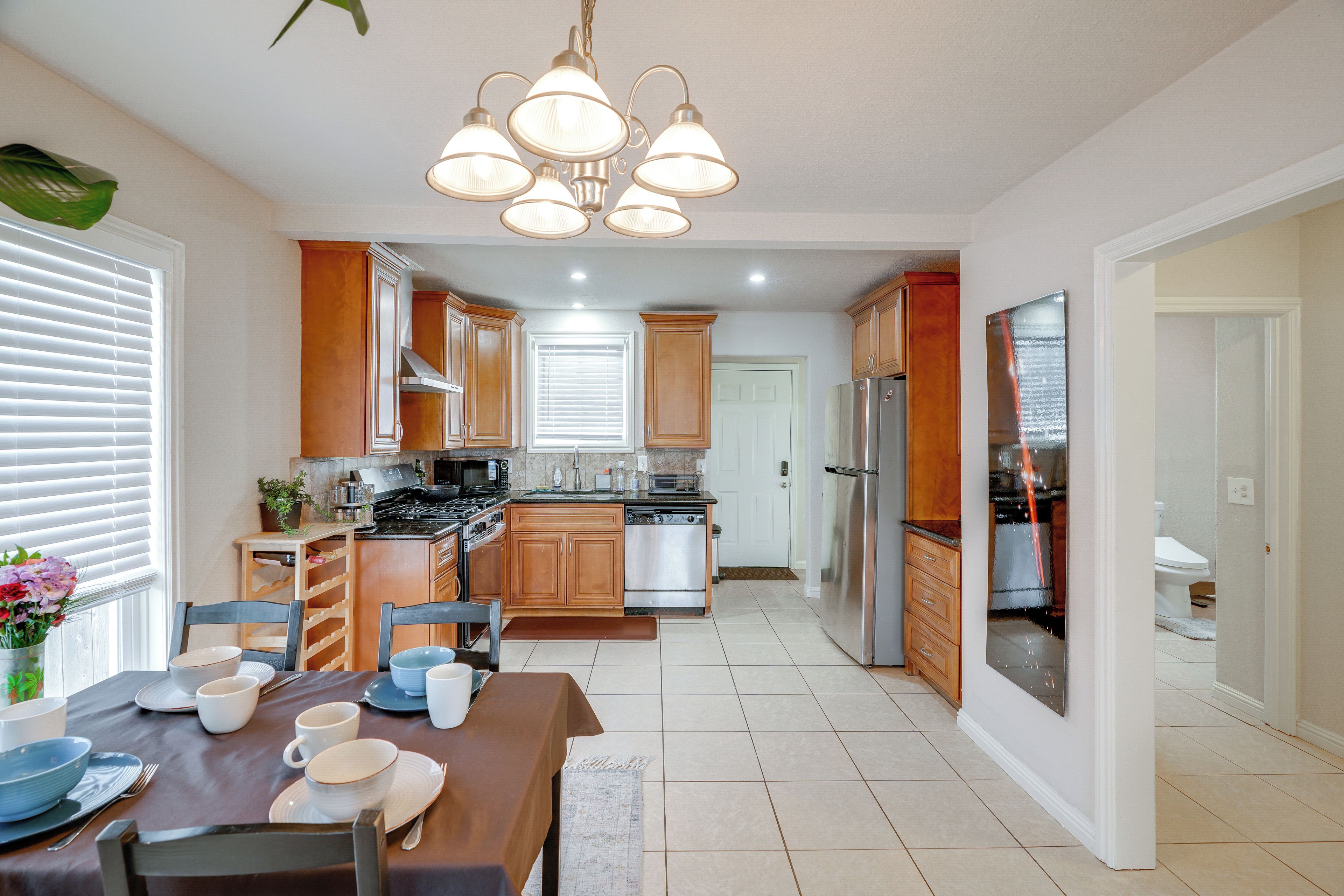 A modern kitchen with wooden cabinets, stainless steel appliances, and a dining area with a table set for four.