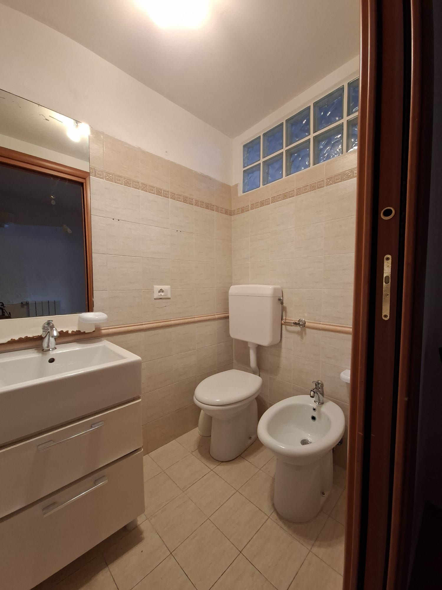 Un bagno con lavandino, WC, bidet e specchio.