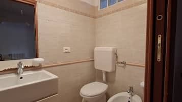 Un bagno con lavandino, WC, bidet e specchio.