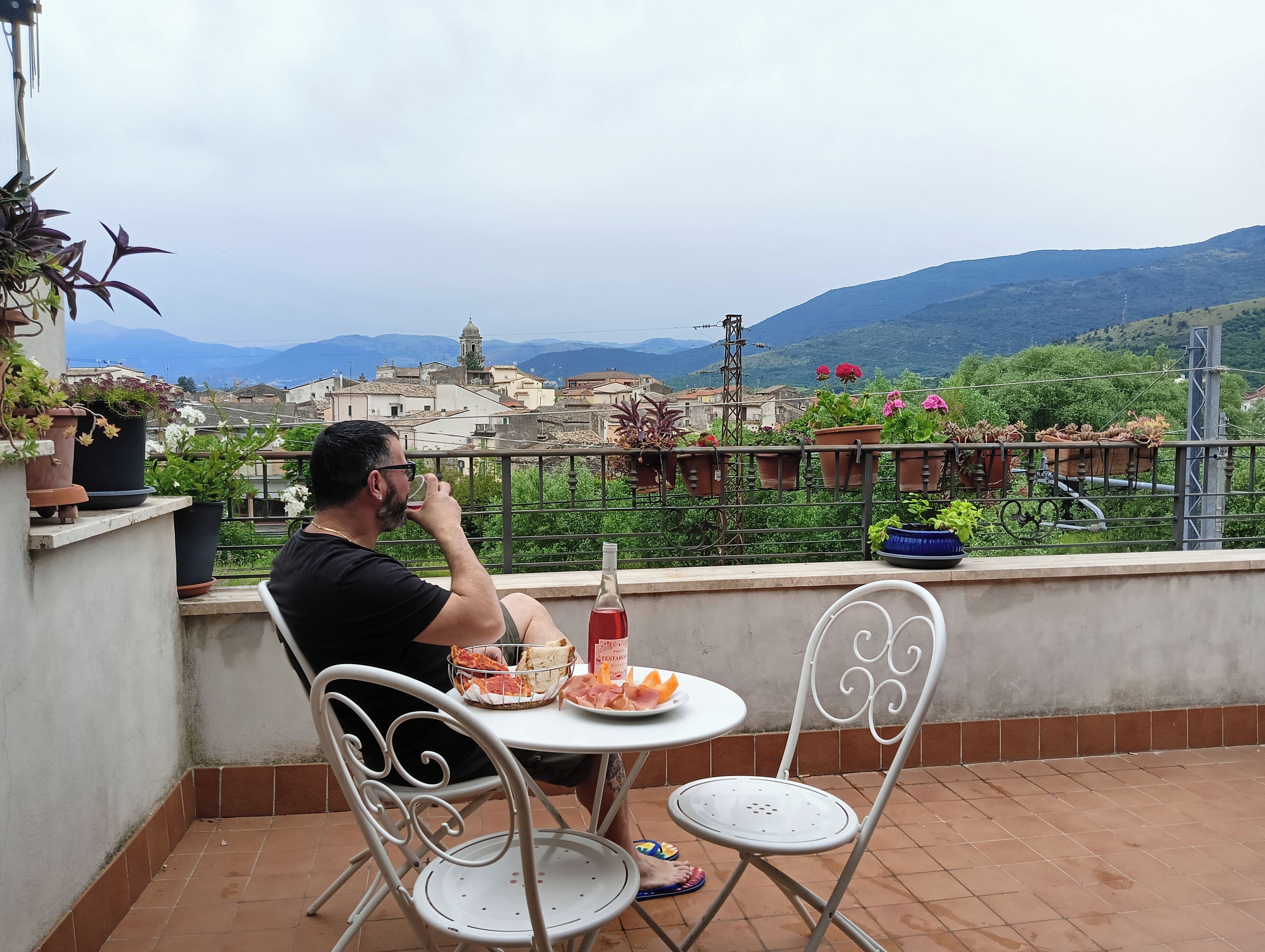 Una persona seduta a un tavolo con vista su una città e montagne sullo sfondo.