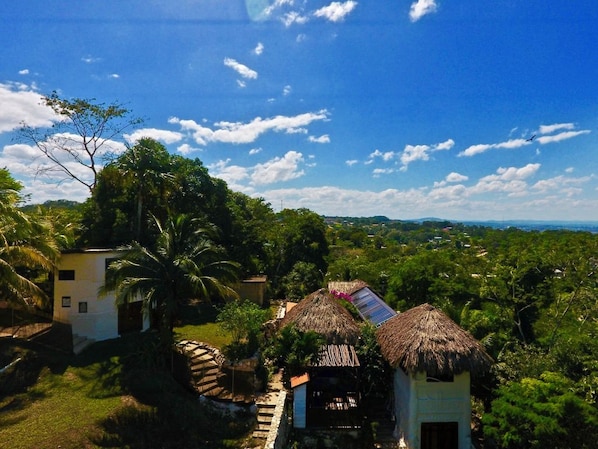 A rural landscape with thatched-roof huts, lush greenery, and a clear sky.