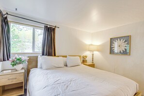 A bedroom with a bed, a nightstand, a lamp, a window with curtains, and a wall-mounted flower decoration. - Mtn-view Cabin Escape in Heart of Grand Lake (Grand Lake)