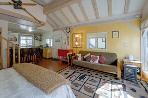Un salon chaleureux avec un canapé, un tapis à motifs et un coin repas comprenant des chaises et une table.