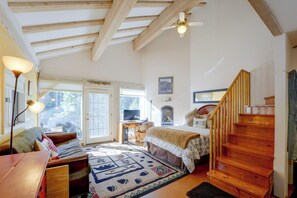 A cozy room with a bed, a desk, a computer, a fireplace, and a staircase. - Mtn-view Taos Ski Valley Condo: 2 Mi to Slopes! (Taos Ski Valley)